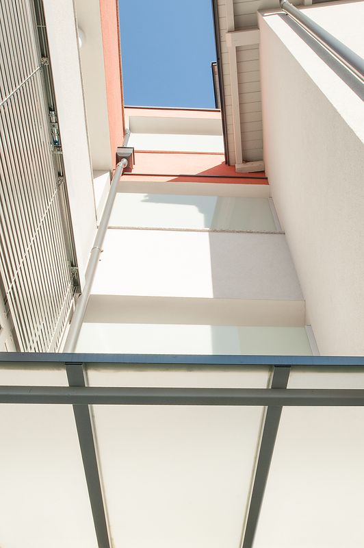 Blick nach oben zwischen Balkonen mit Glasbrüstung