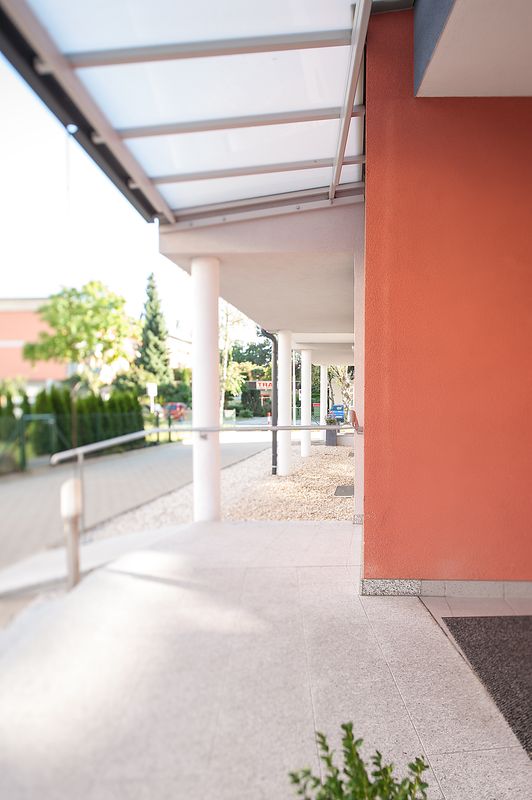 Hauszugang mit Glasvordach und roter Wand