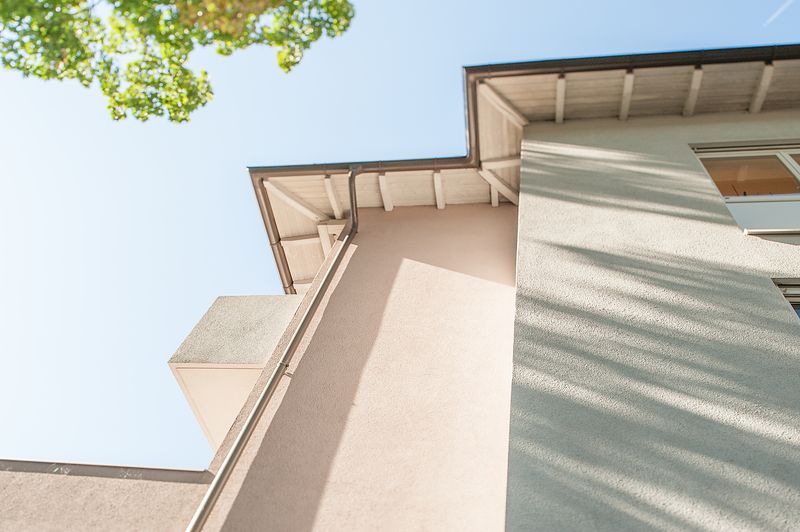 Hausecke mit Dachvorsprung vor blauem Himmel