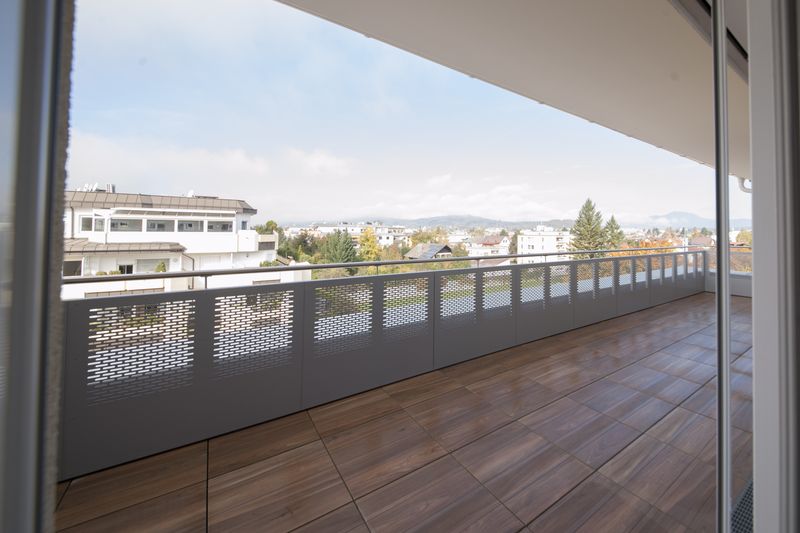 Loggia mit Holzboden und Blick über die Stadt auf die Berge